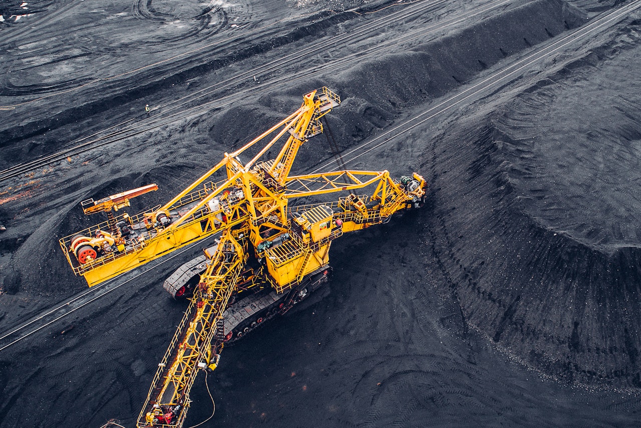 A photograph of a large coal mine and yellow heavy machinery